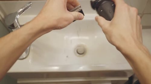 Disassembling a Black Electric Razor Over a Sink