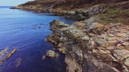 Stunning aerial view of rocky coastline meeting calm blue waters