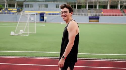 the Guy Walks Around the Stadium Smiles and Looks Into the Camera Side View