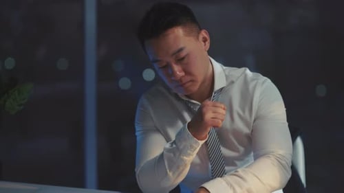 Stressed man in office adjusts his tie