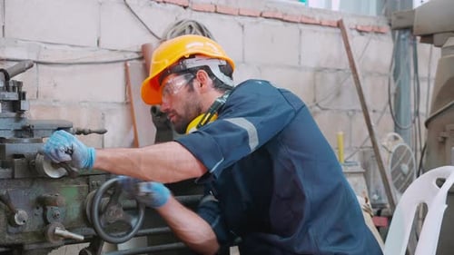Young caucasian engineer man operating lathe machine for preparing production at factory.