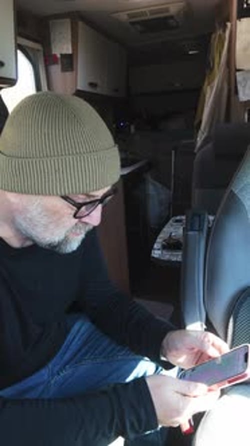 Camper traveler uses mobile device for online communication on journey.