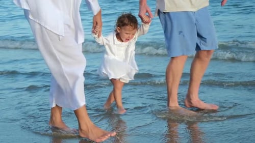 Family on Vacation By the Sea Dad and Mom Hold the Hands of the Baby and Walk on the Water Family on
