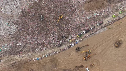 Aerial view of massive landfill with excavators moving garbage