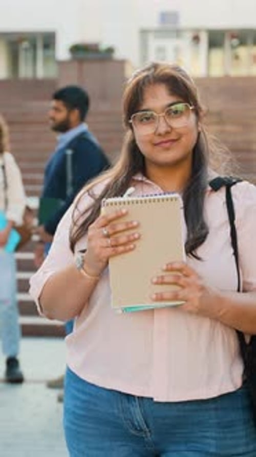 Student holding notebooks on college campus