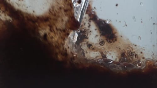Water Pours Into Brown Powder Substance In Clear Container