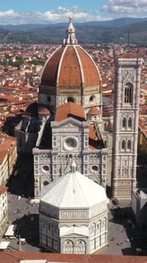 Vertical aerial view of Cathedral of Santa Maria del Fiore zooming in with city and mountains on a