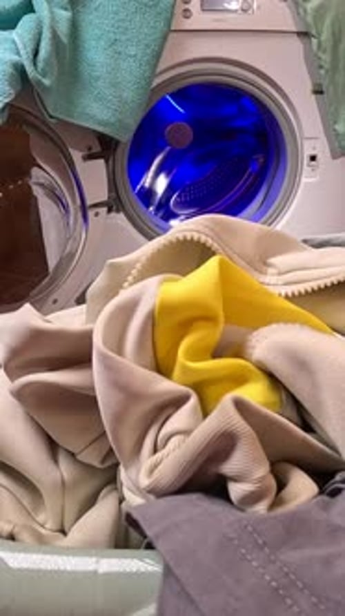 Vertikales Video: POV-Haushälterin lädt Kleidung in die Waschmaschine
