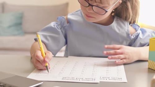 Child Completing Math Worksheet at Desk Indoors