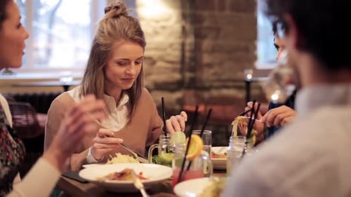 Friends Laughing, Talking and Eating in Restaurant