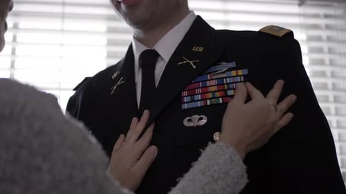 Loving wife touches ribbon bar on military officer husband jacket indoors