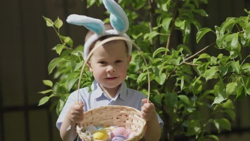 Funny Kid Boy Easter Bunny Ears Holding Basket Full of Colorful Easter Eggs
