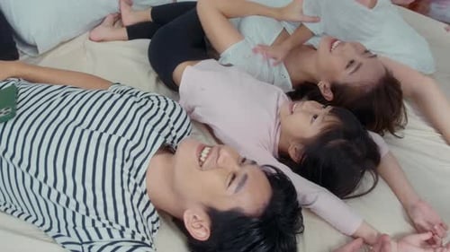Happy Family Lying on Bed Together