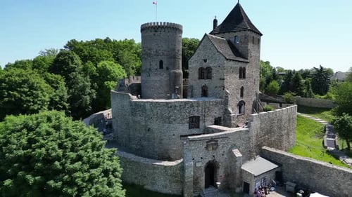 Medieval castle with a turret, white stone walls, and courtyard during a beautiful summer day surrou