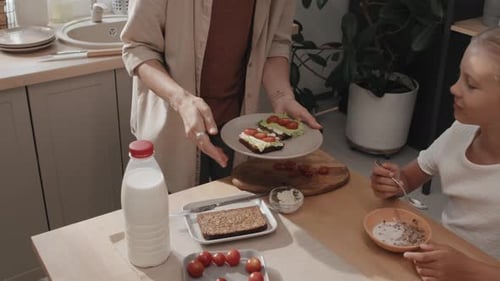 Woman Making Sandwiches for Child at Breakfast Table