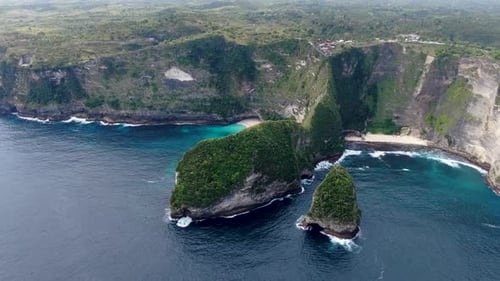 Small sandy beaches with high rocky cliff behind in Indonesia island, aerial view
