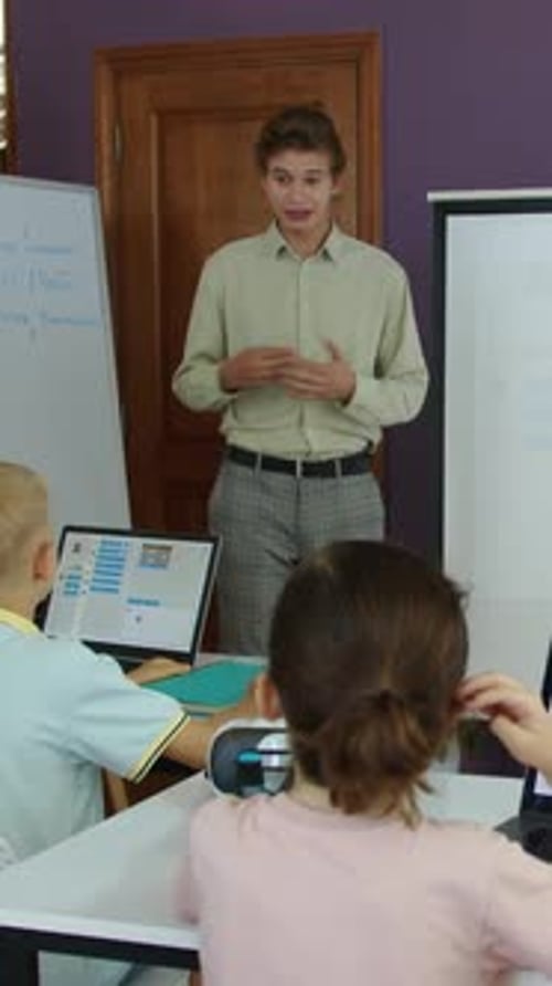 Lehrer erklärt einer Gruppe von Kindern im IT-Kurs das Thema