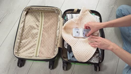 Man packing his suitcase for long journey with wad of money. Guy closes the green baggage case