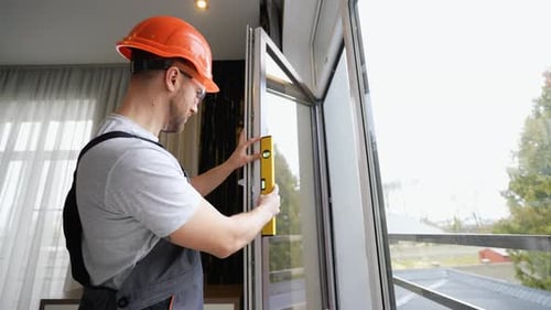 Fensterinstallateur passt Kunststofffenster mit Nivellierwerkzeug im Zimmer zu Hause an