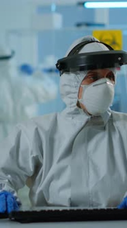 Scientist Wearing Hazmat Suit Typing on Keyboard in Lab