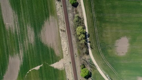 Bahnstrecke, umgeben von symmetrischem Ackerland, Drohnenflug
