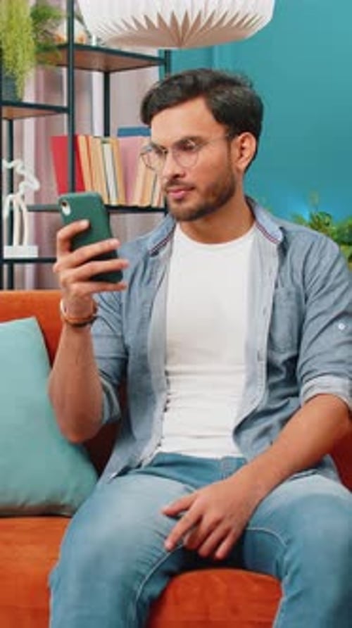 Man Relaxing on Sofa Using Mobile Phone Indoors