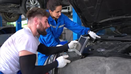 Professional auto mechanic man and woman working together in auto repair shop.