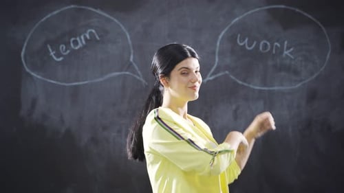 Woman Gives Thumbs Up Before Chalkboard with Teamwork Words