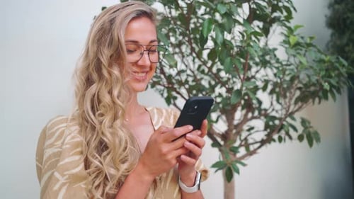 Happy Woman Checking Social Media While Using Smartphone in City