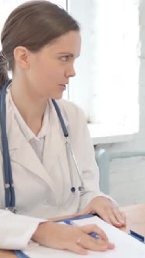 Female Doctor Talking and Taking Notes in Office