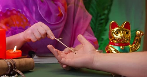 Woman does client palm-reading using magical wooden twig