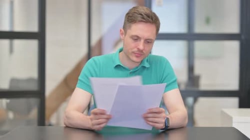 Mature Adult Man Reading Documents in Office