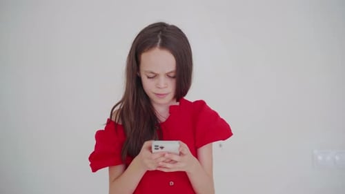 Girl Engrossed in Smartphone Against White Wall