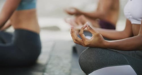 4k video footage of a group of unrecognizable people meditating and doing yoga at the beach