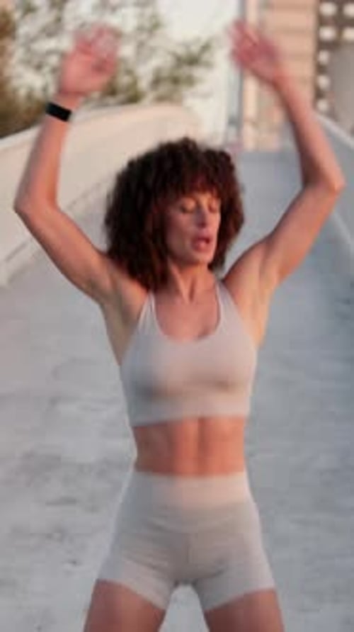 Vertical video, Young Woman Stretching on a City Bridge