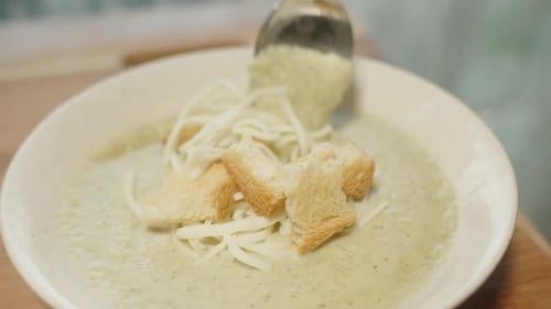 Cauliflower puree soup, with croutons and cheese, A woman eats with a spoon. Close-up.