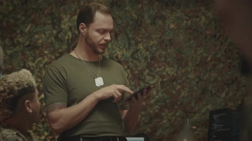Man Using Tablet With Associates in Camouflage Room