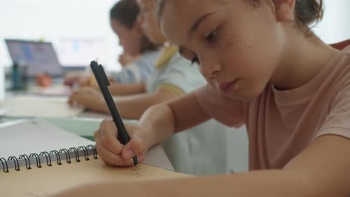 Cute Caucasian Girl Drawing in Notebook at School