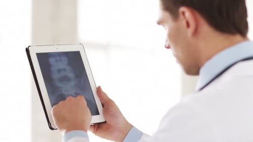 Professional doctor examining x-ray scan on tablet pc in modern hospital lab