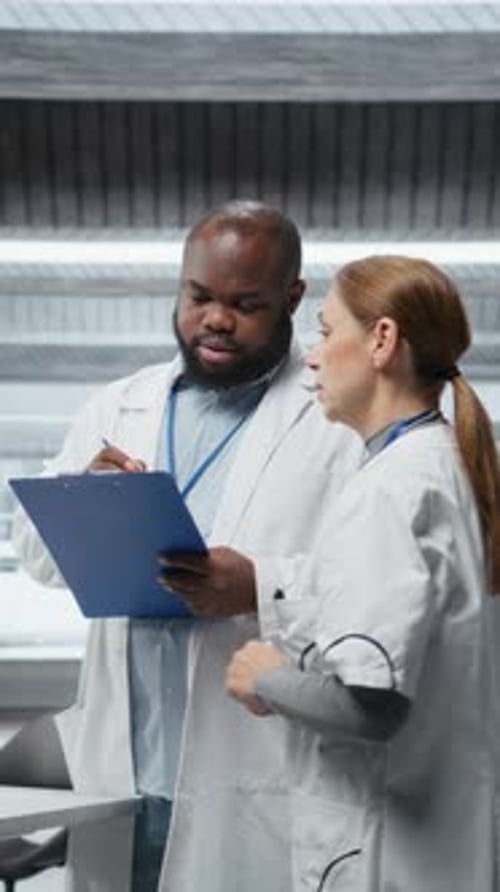 Doctors Discussing Notes on Clipboard in Hospital Setting