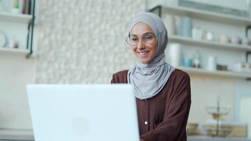 Smiling Woman Wearing Hijab Works on Laptop
