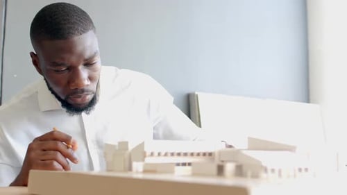 Architect working on building model, focusing on design details in office, copy space