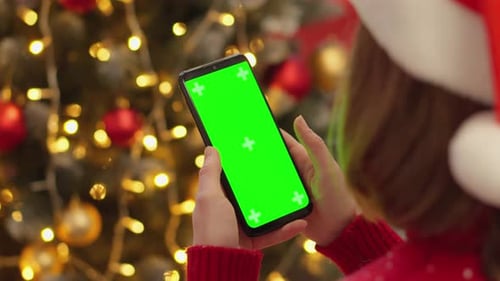 Woman Holding Smartphone in Front of Christmas Tree
