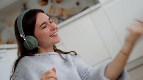 Woman Dancing with Headphones in Bright Kitchen