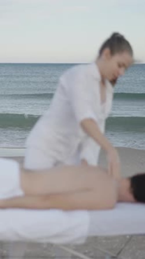 Sea Waves in the Background and Woman Performing Massage on the Foreground Unfocused