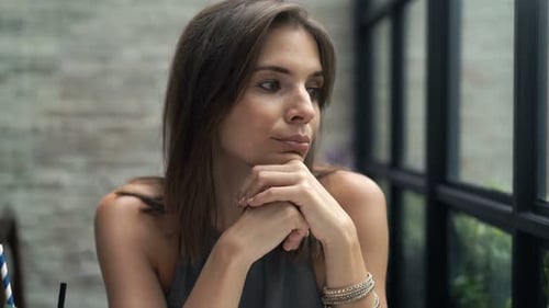 Young, Pensive Woman Sitting in Cafe 30s