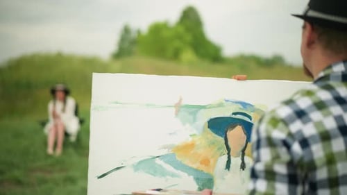 Painter in Checkered Shirt Painting in a Field with Seated Woman in Background