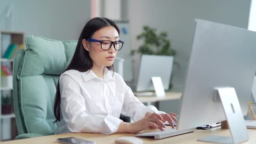 Exhausted, overworked asian office worker sitting in the workplace with severe headache massaging