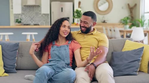 Young Couple Laughing and Chatting on Couch at Home