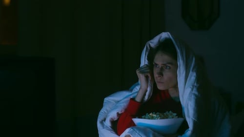 Woman Watching TV Under Blanket Eating Popcorn